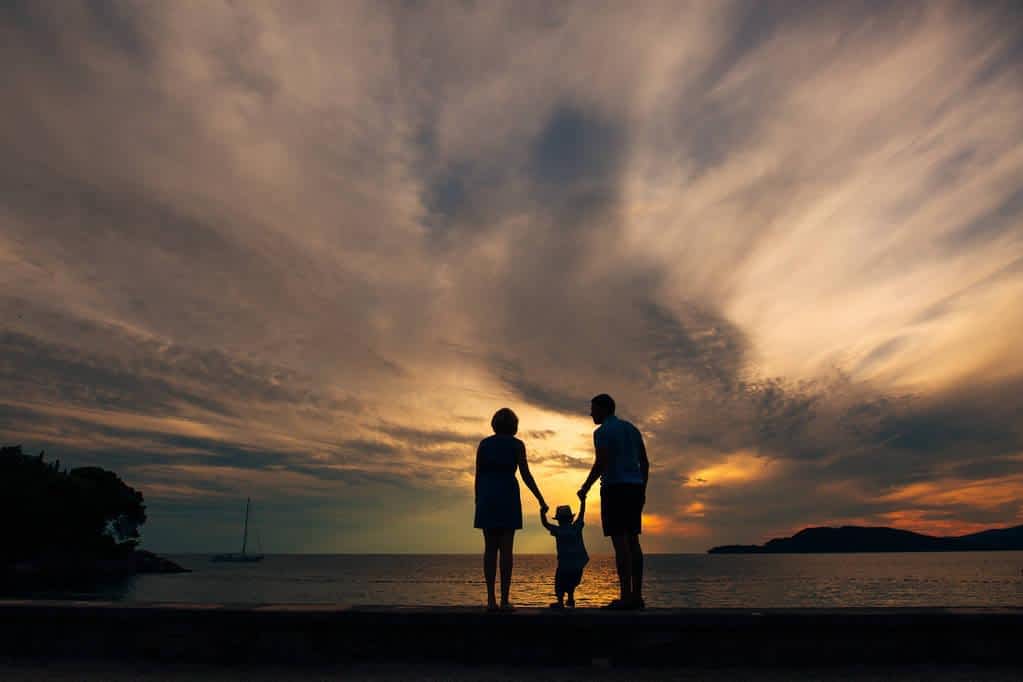 Helicopter Parenting and Narcissism: The Hidden Connection 5 silhouette of parents with a child at sea family on the beach