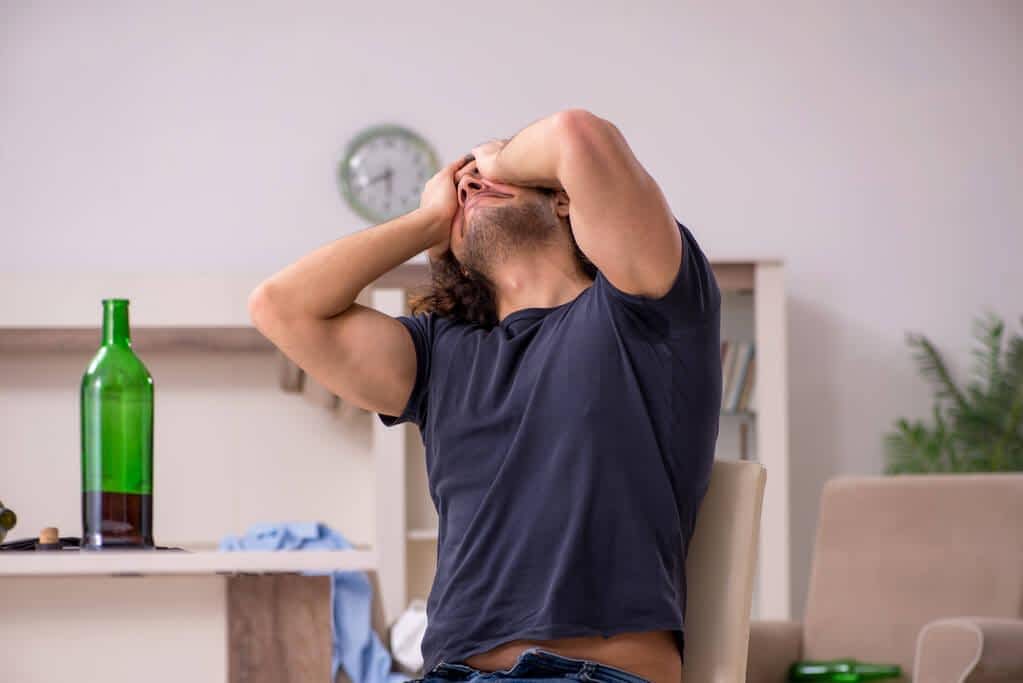 young unemployed man drinking alcohol at home