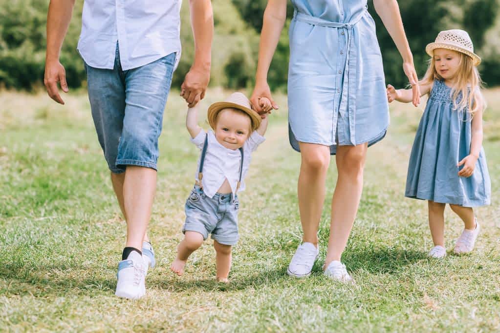 Helicopter Parenting and Narcissism: The Hidden Connection 11 parents holding hands children walking green feild together