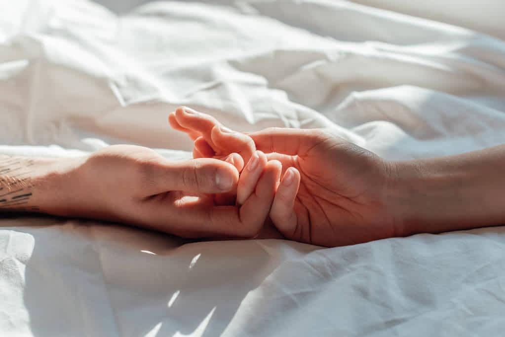 couple live holding hands while lying bed