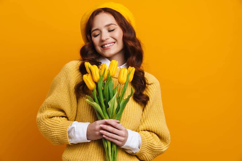 smiling young woman long red hair sweater beret standing holding
