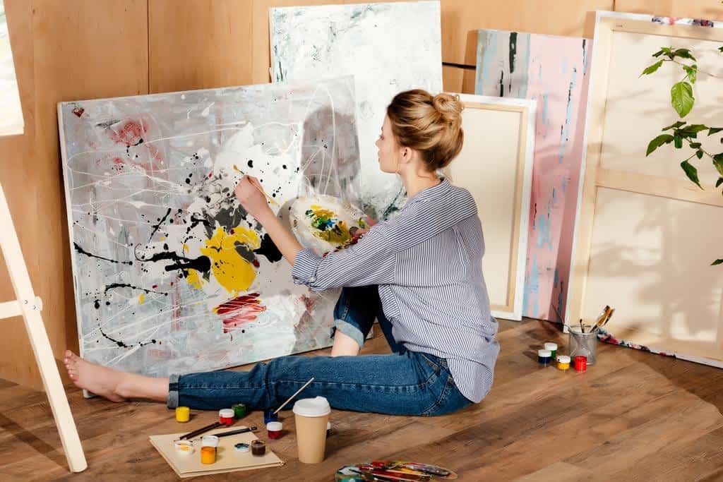 beautiful young female painter sitting floor drawing picture art studio