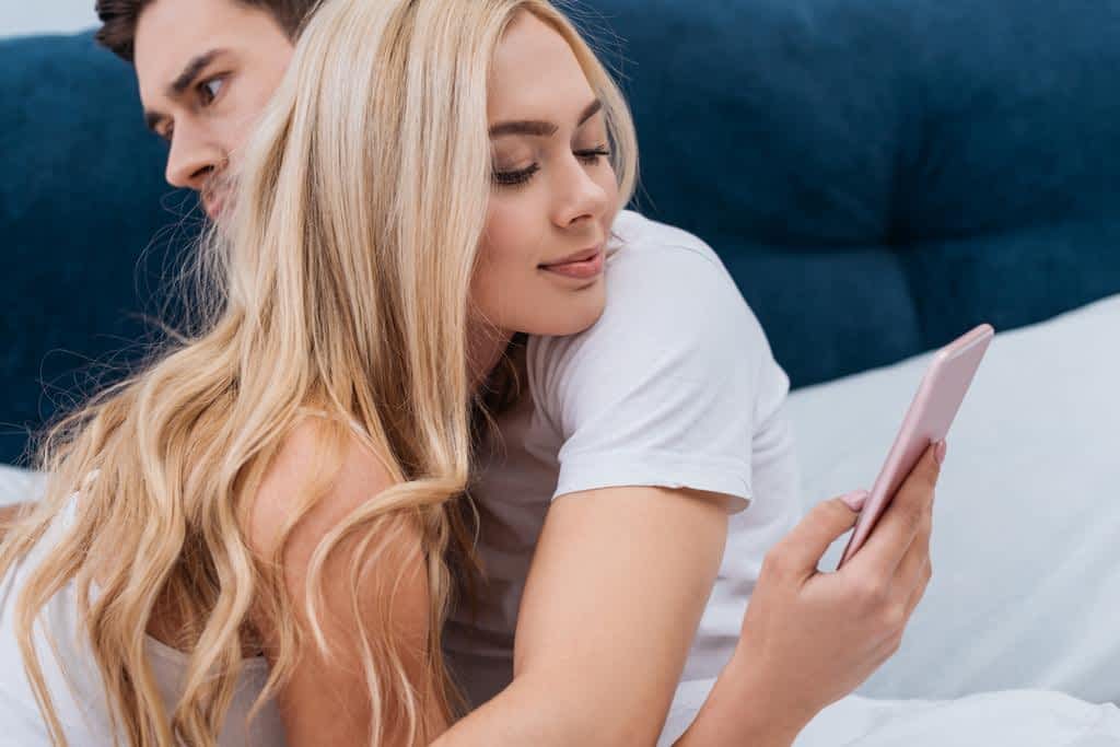 The Truth Behind Walkaway Wives: Debunking 7 Absurd Myths 6 stock photo smiling young woman using smartphone hugging husband bed relationship problem