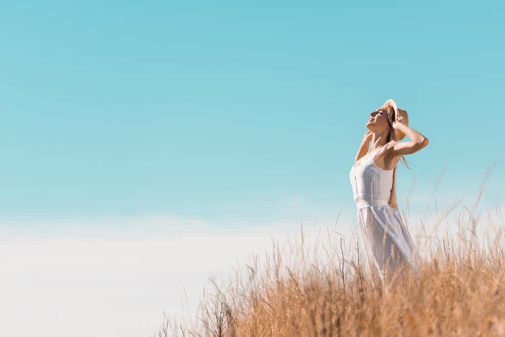 young woman white dress touching straw hat