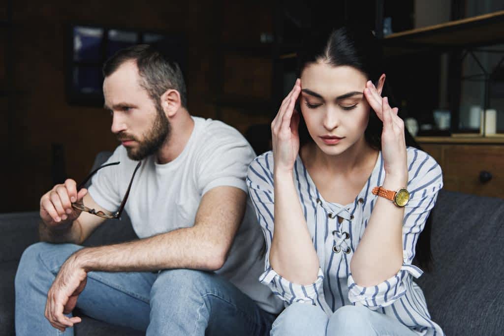 sad young couple sitting sofa home quarrel