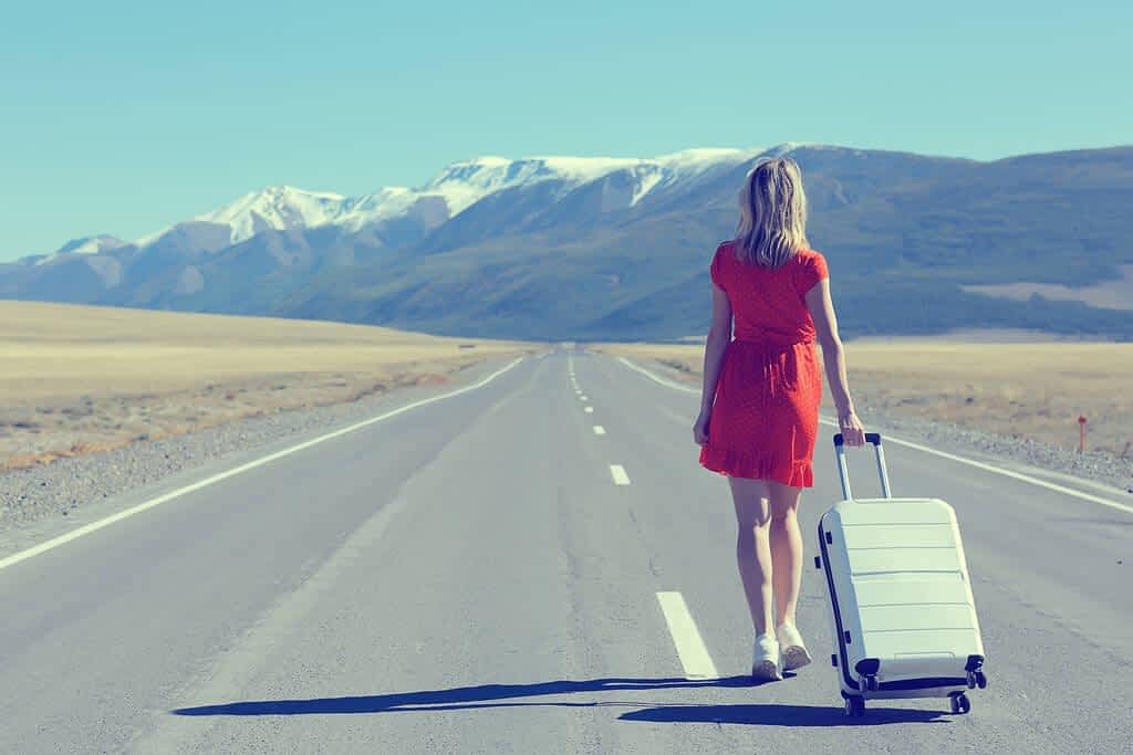 girl walking highway luggage suitcase travel view back landscape america