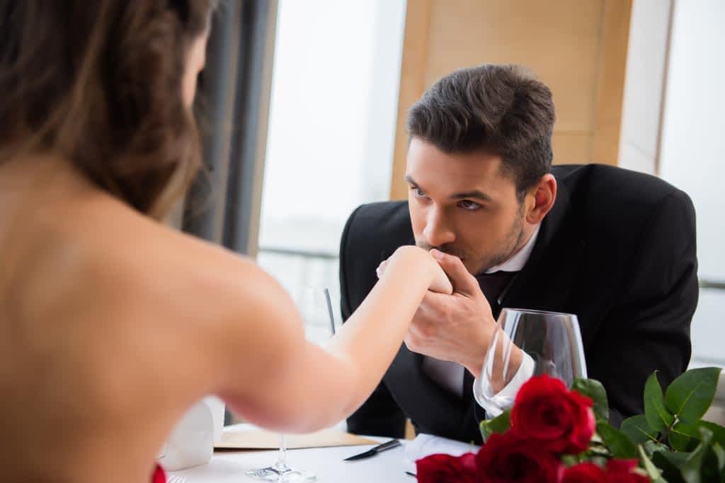 partial view man kissing girlfirend hand romantic date restaurant valentine