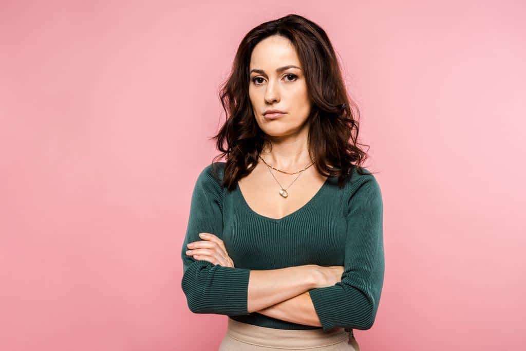 upset woman standing crossed arms isolated pink