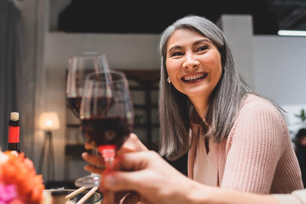 The 11 Unexpected Silver Linings of a Gray Divorce 7 smiling attractive asian woman clinking friend dinner