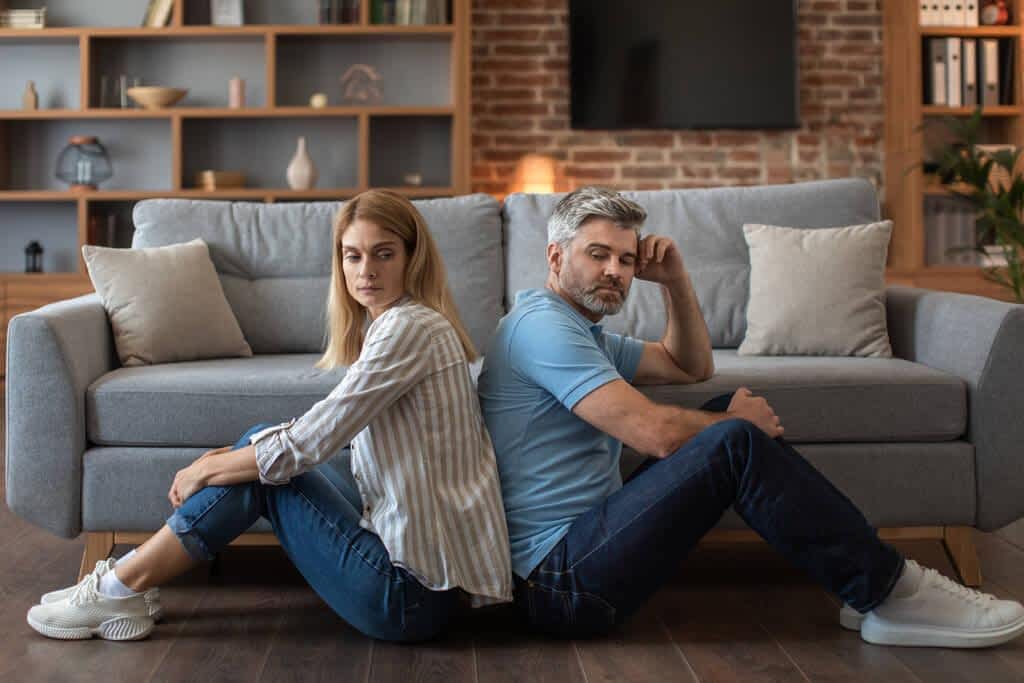 unhappy mature caucasian male beard ignores offended woman sit floor