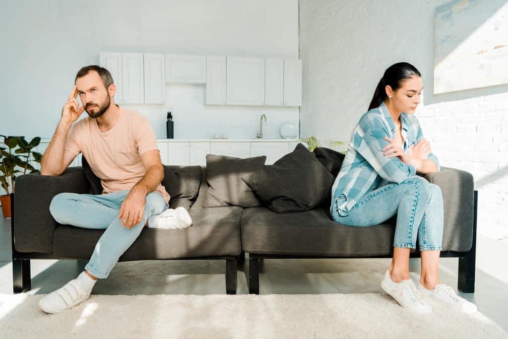 couple having disagreement sitting ends sofa