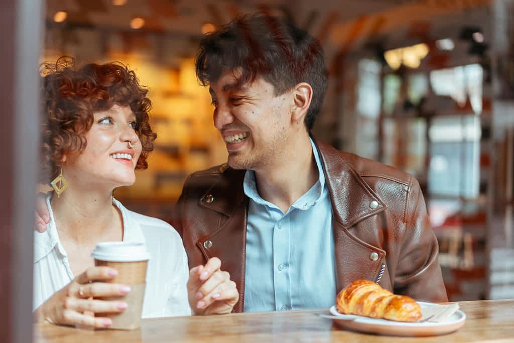 man andwoman smiling at each other in a coffee shop