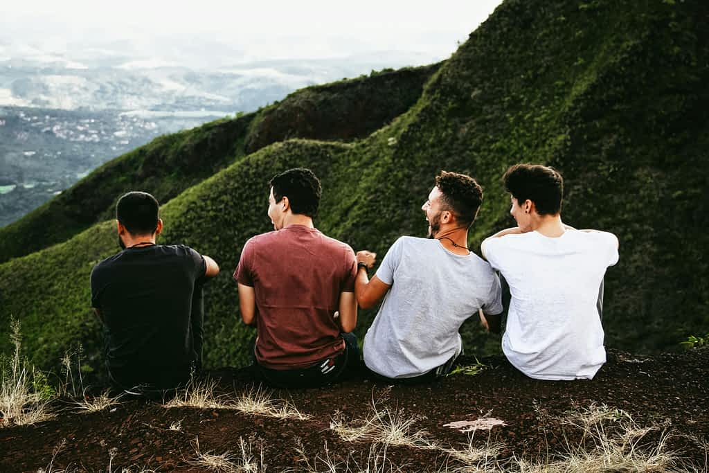 6 Ways Men With Father Issues Struggle to Connect 7 4 men who are friends sit on top of a hill laughing