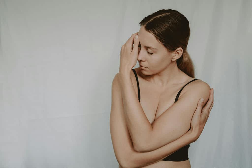 upset unhappy woman standing with her arms wrapped around her