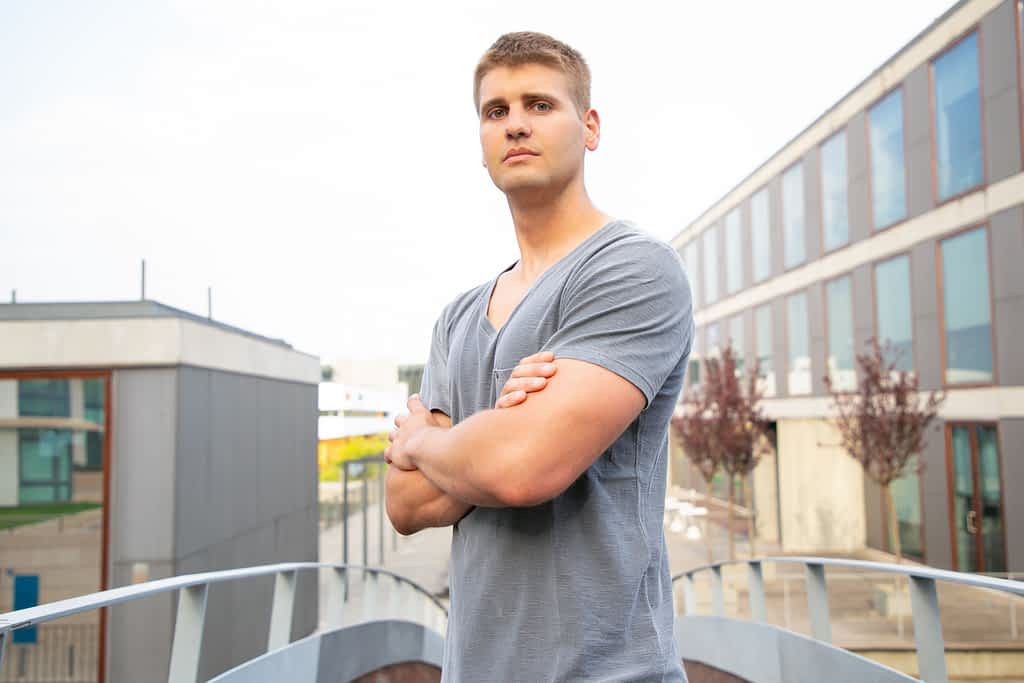 Connection Between the Dismissive Avoidant and Intimacy Issues Exposed 4 Proud successful well built guy standing for camera with crossed arms. Young Caucasian man in casual posing near city building and looking in camera. Confident young man concept