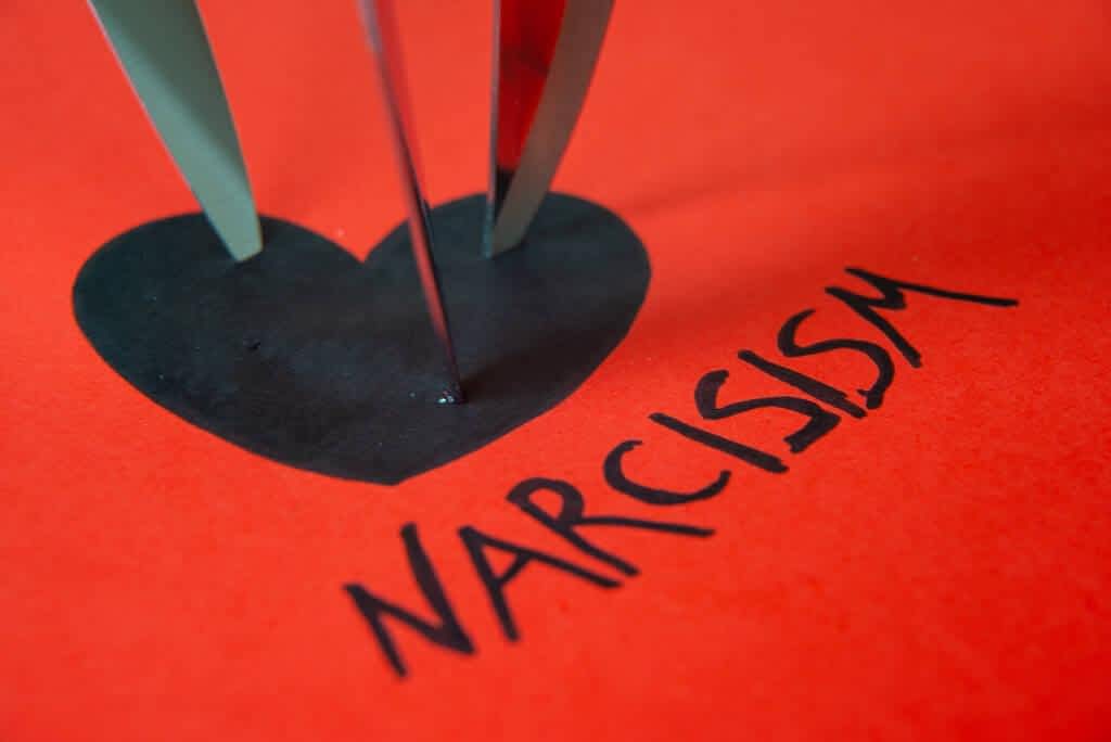 word narcisism written black red paper next black heart drawing