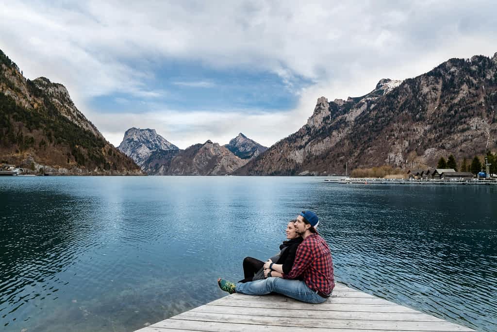 couple sitting on a dock while on a date by the lake