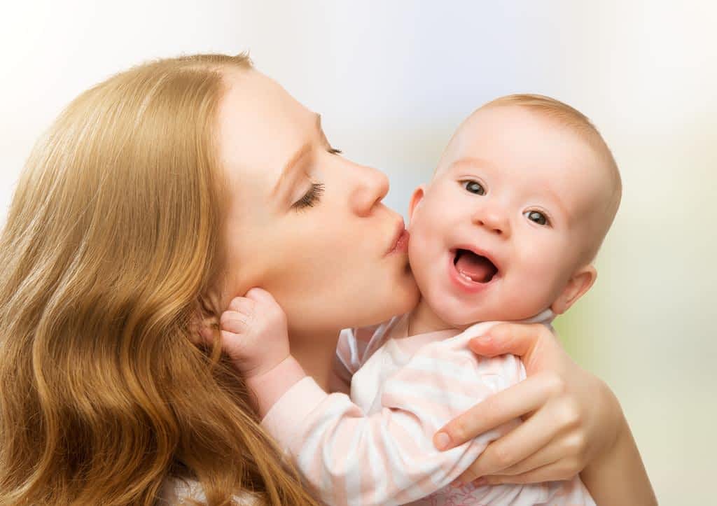 happy cheerful family mother and baby kissing