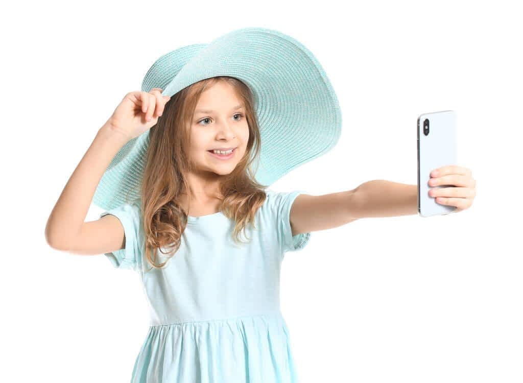 cute little girl taking selfie on white background