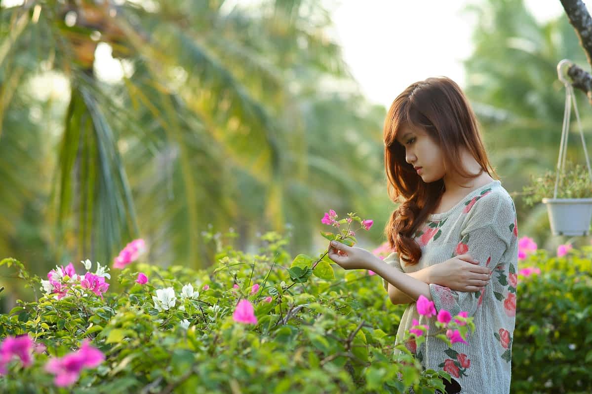 Young woman looks at flower in a garden