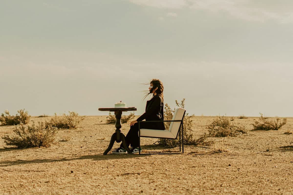 woman sits on a chair alone in the desert