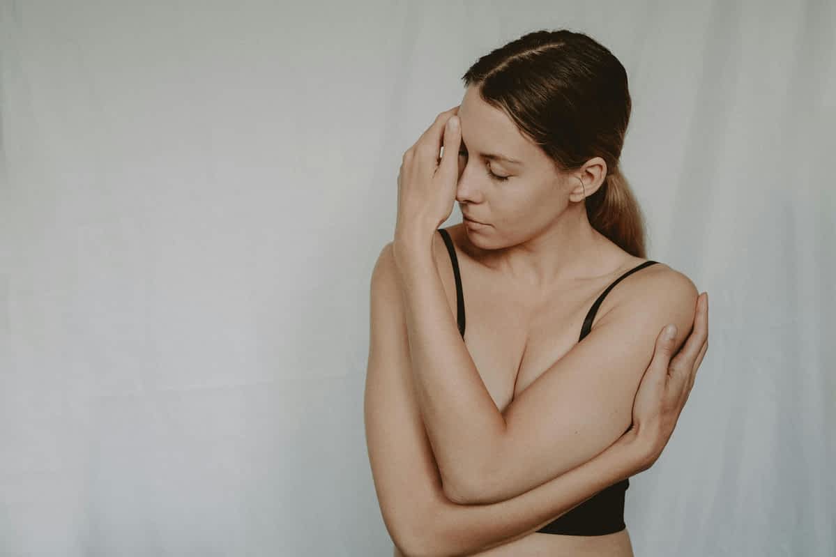upset unhappy woman standing with her arms wrapped around her