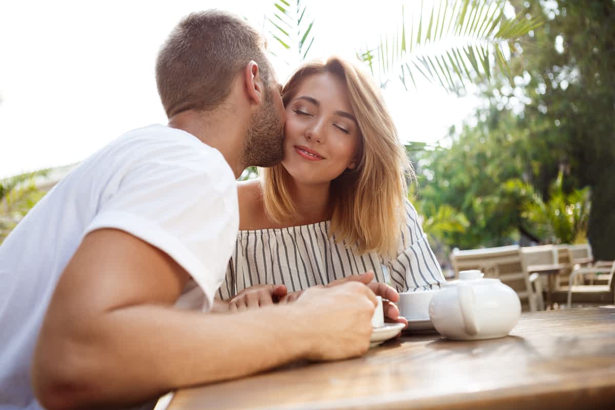 High value woman demonstrating self-respect on date, smiling and drinking tea with man in cafe