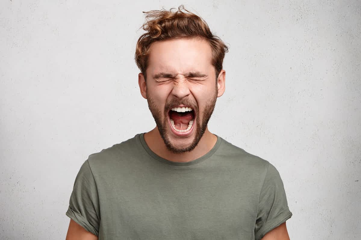 angry man screaming with eyes closed