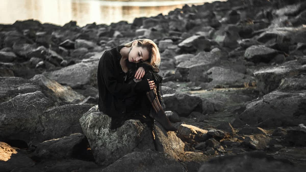 sad woman sitting on rocks near the coast