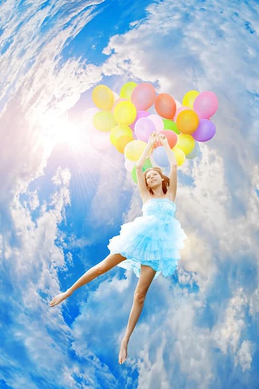 woman holding balloons against sun