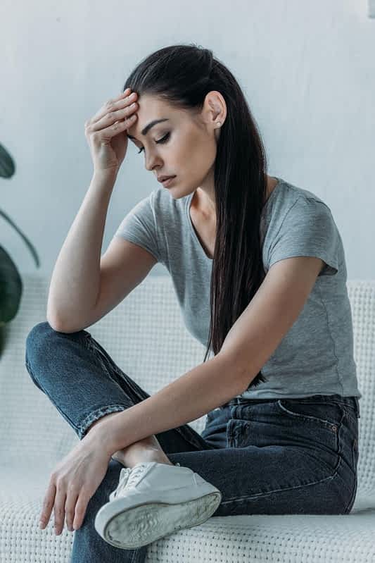upset young woman hand forehead sitting couch looking