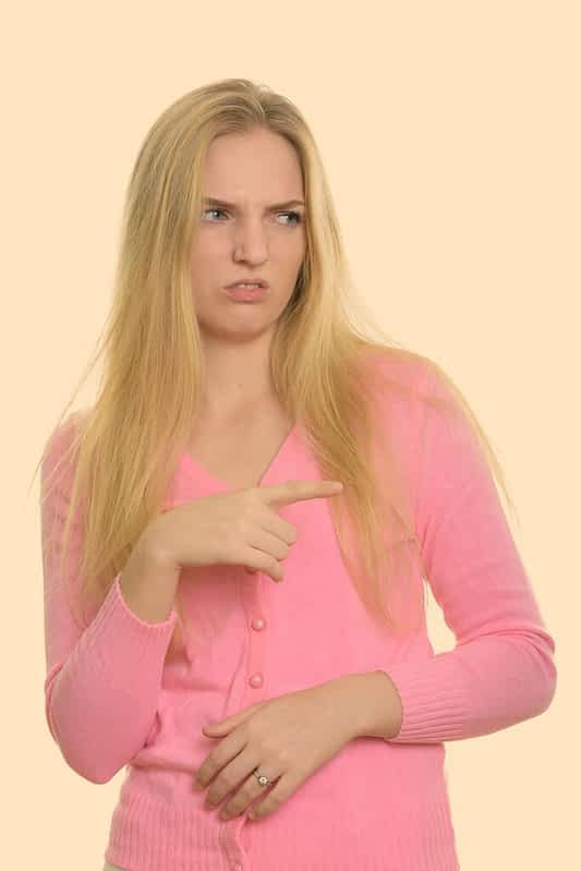 young beautiful teenage girl pointing finger and looking disgusted
