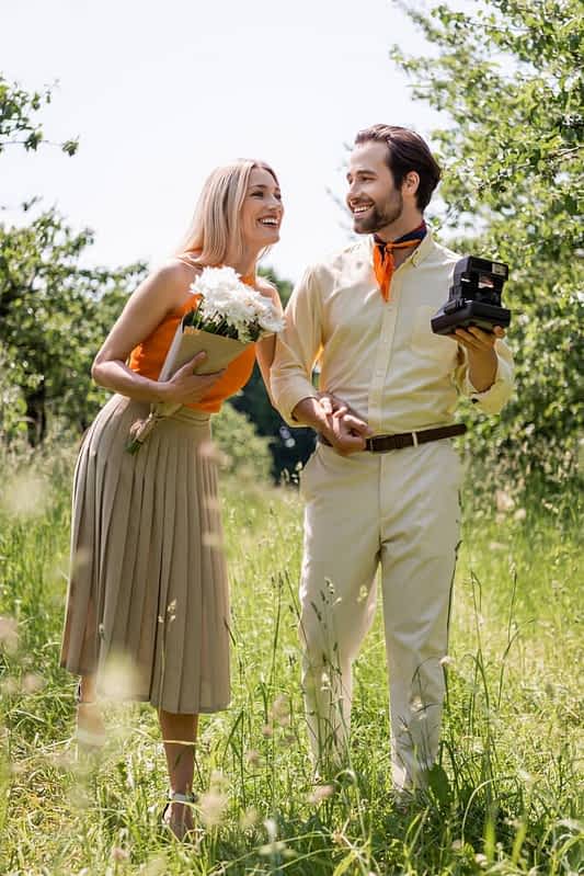 2026’s Most Toxic Dating Trends: Behaviors You Need to Avoid 14 smiling stylish couple bouquet vintage camera holding hands park