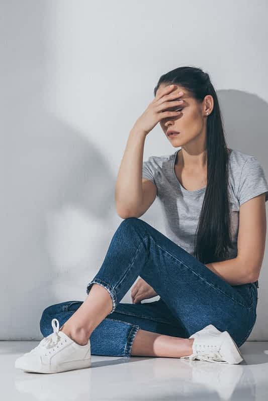 full length view depressive brunette girl sitting hand face