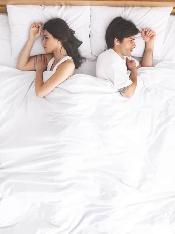 upset couple sleeping separately on their bed 1