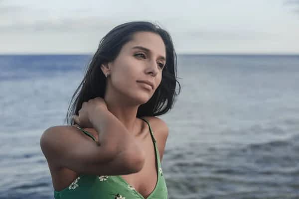 woman with her hand on her neck contemplating the sea