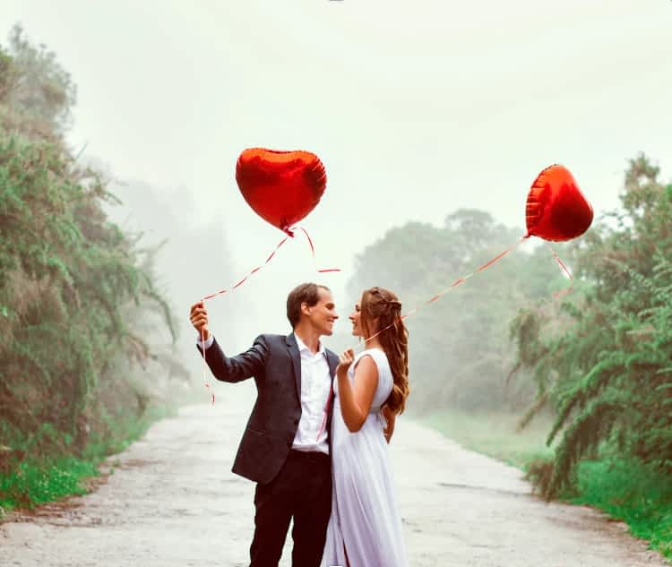 couple outside holding heart shaped balloons