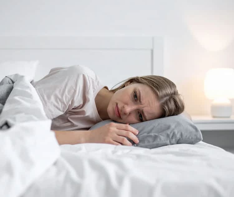 woman laying in bed looking worried