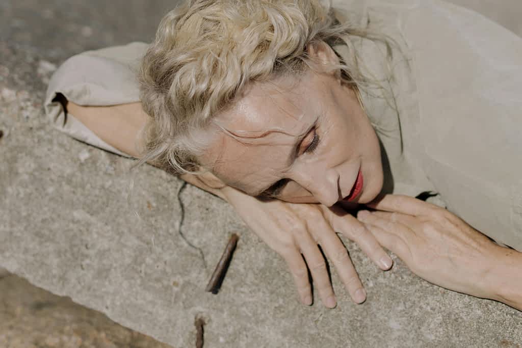 17 Warning Signs Your Marriage Is Failing (And What to Do Next) 2 Exhausted, sad woman leans agains a cemet wall with her eyes closed