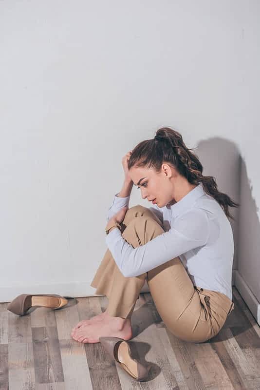 9 Ways Intermittent Reinforcement Keeps You Stuck in Toxic Relationships 3 sad woman white blouse beige pants sitting floor wall home